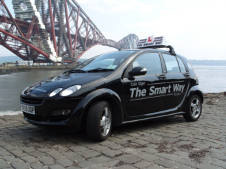 Black Smart ForFour manual training car by the Forth Bridge
